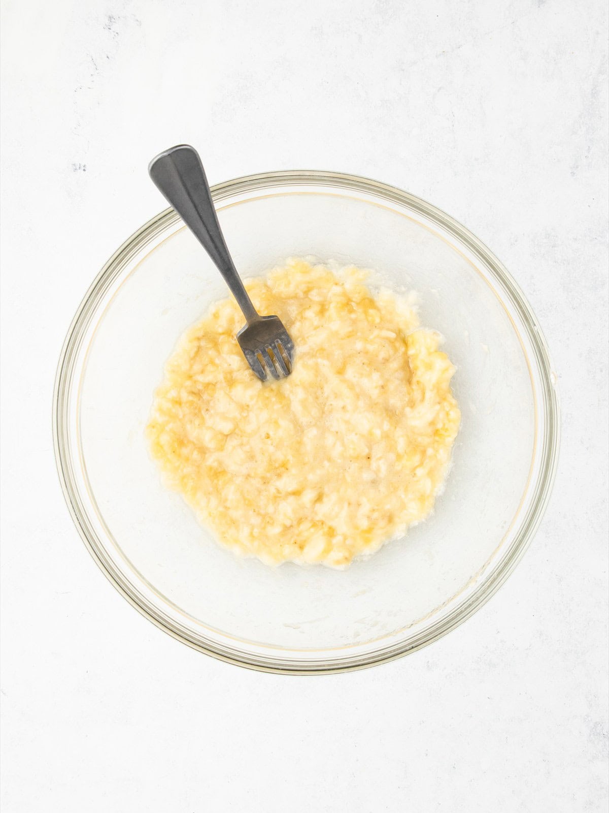 Ripe bananas mashed with lemon juice in a large mixing bowl.