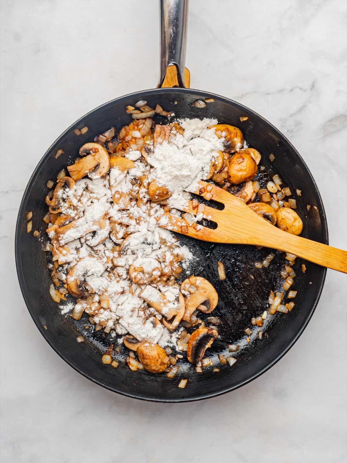 Flour sprinkled over the golden mushroom mixture to thicken the stroganoff sauce.