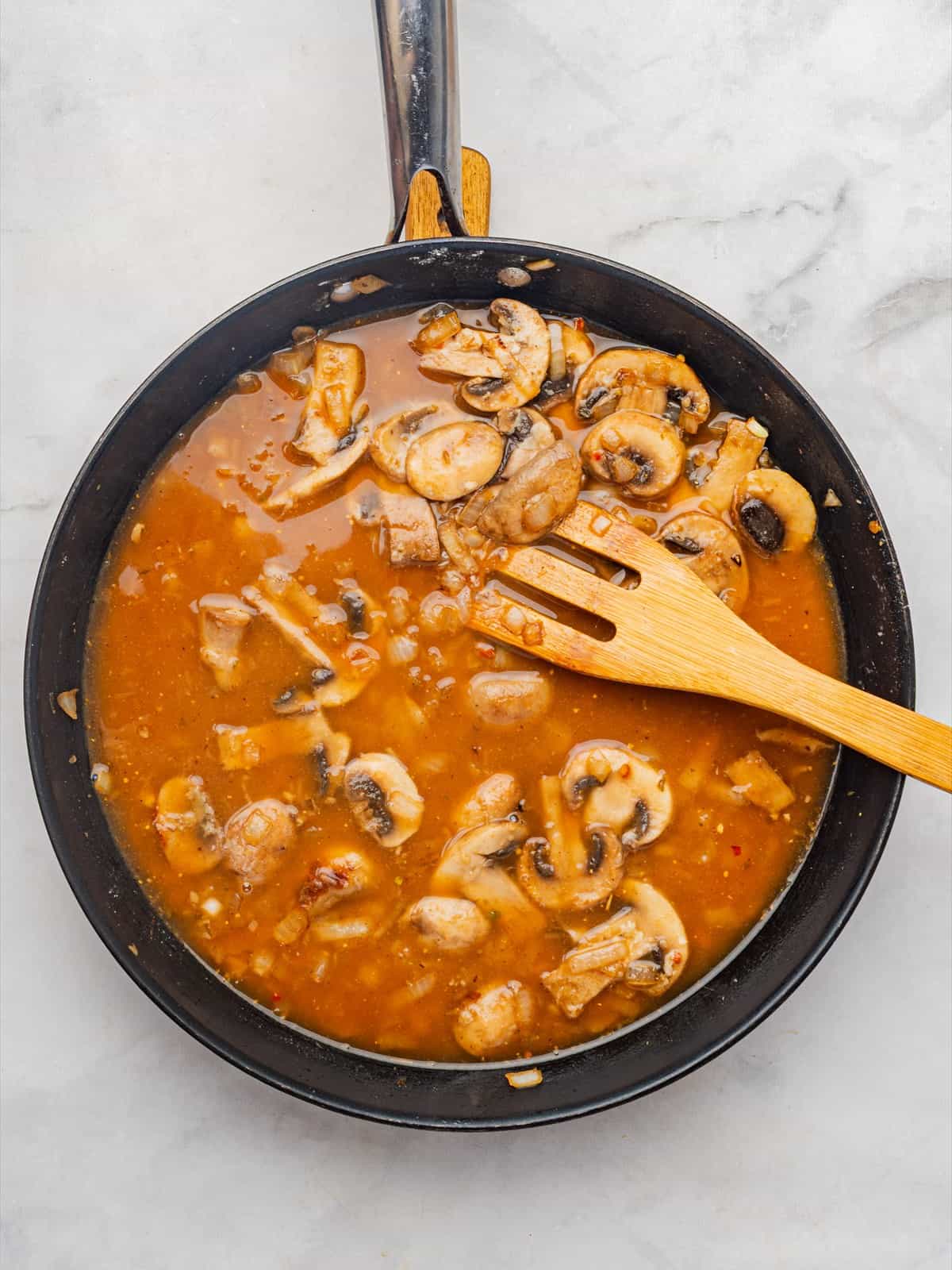 White wine and beef broth added to the skillet and simmering with the mushrooms.