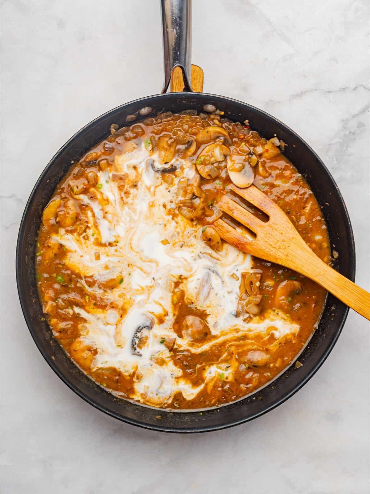 Sour cream stirred into the beef stroganoff sauce until smooth and glossy.