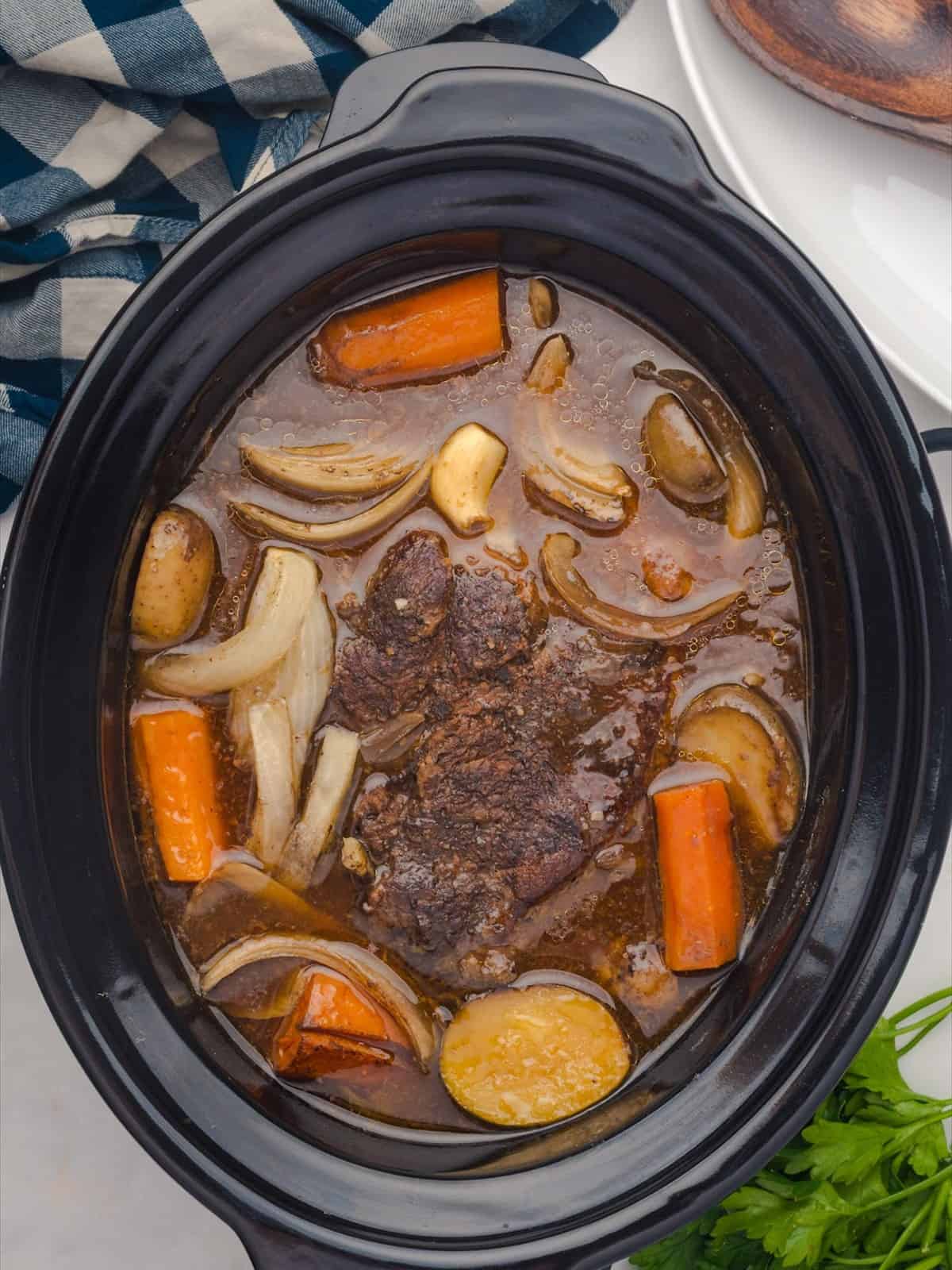 Fork tender crock pot pot roast with carrots and potatoes after slow cooking for eight hours.