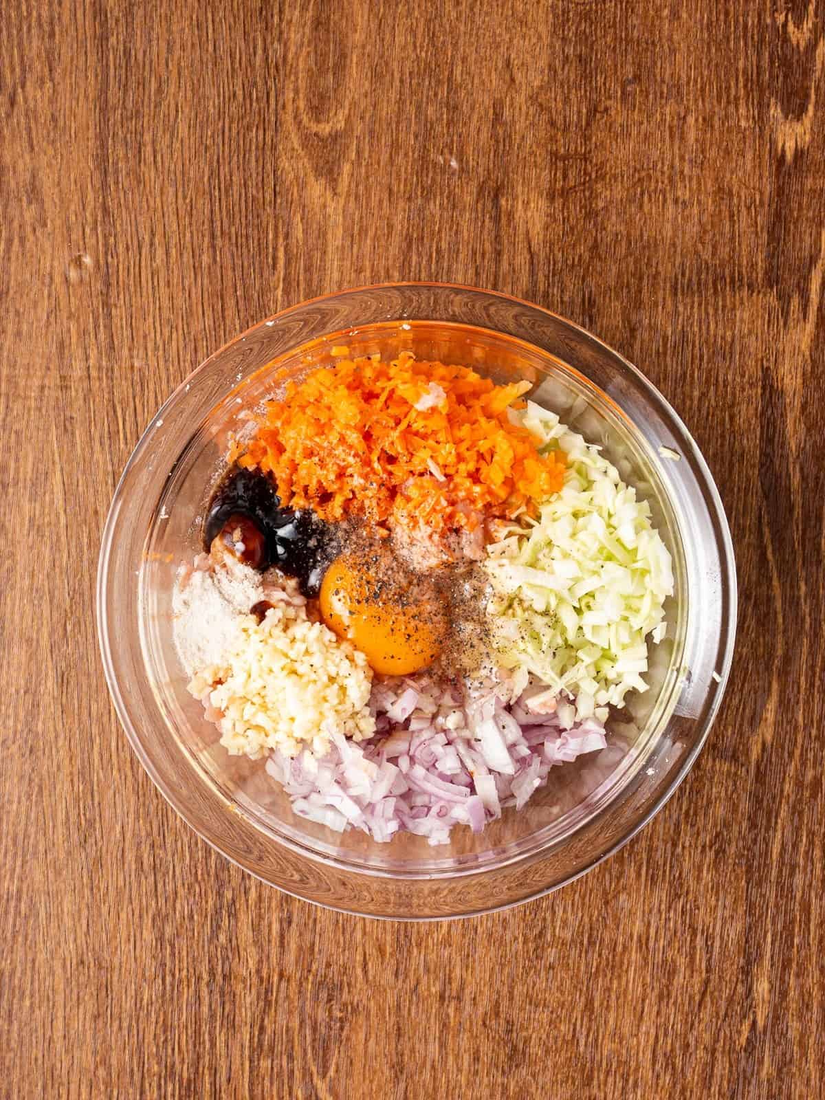 Ground pork, carrot, cabbage, onion, garlic, egg and seasonings in a glass mixing bowl