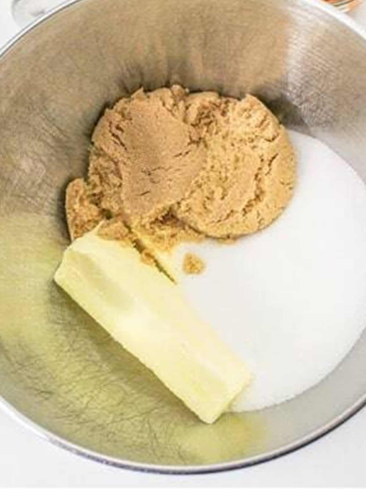 Unsalted butter, granulated sugar, and brown sugar in a stand mixer bowl for pumpkin cookies.
