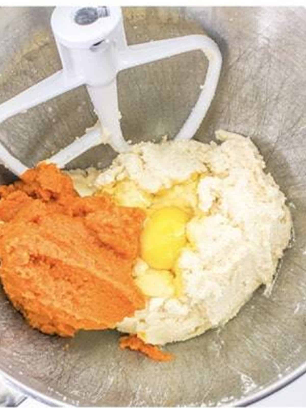 Adding pumpkin puree and an egg to the creamed butter and sugar for pumpkin cookie dough.