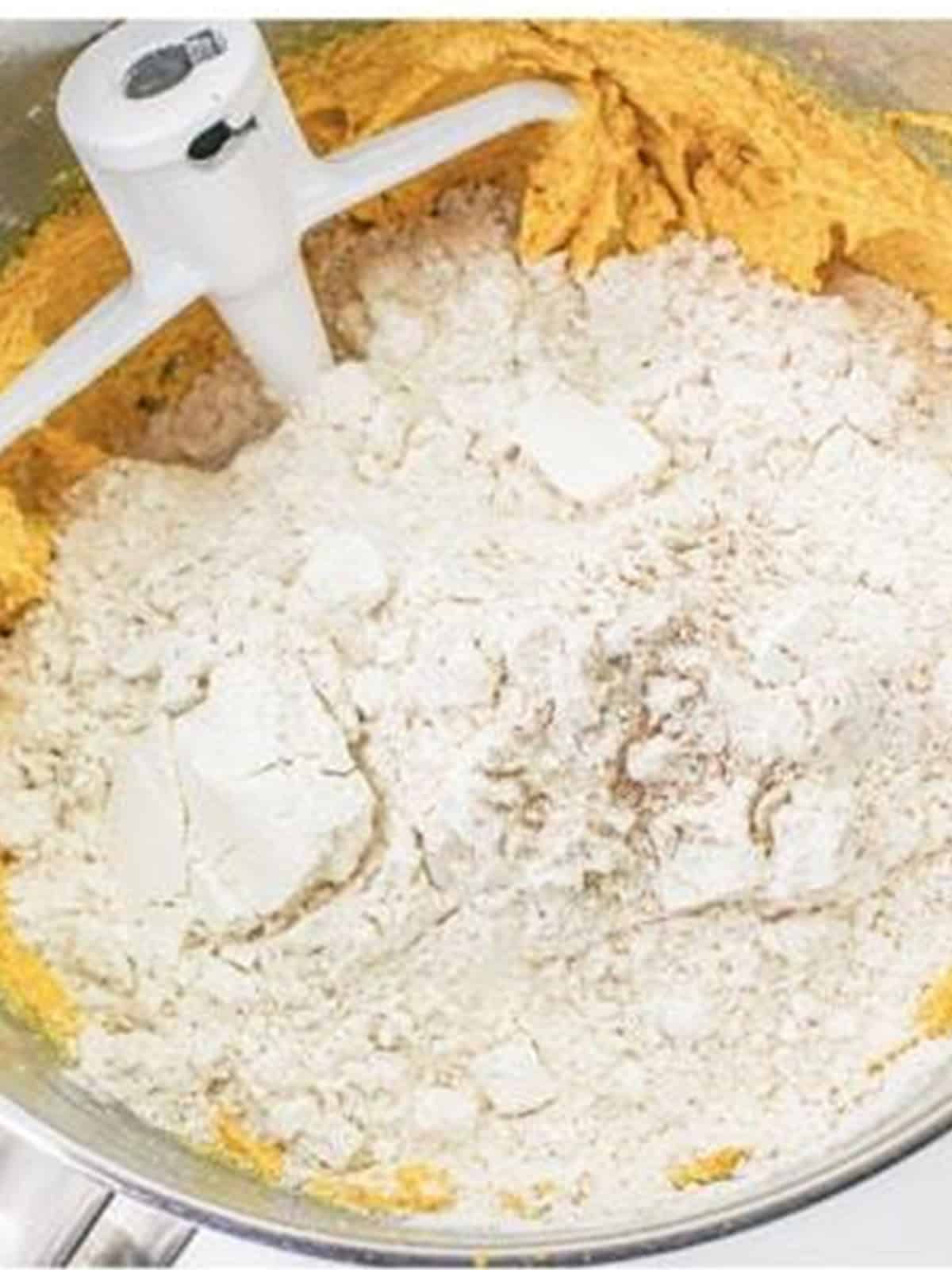Adding the flour mixture to the wet ingredients for pumpkin cookie dough.
