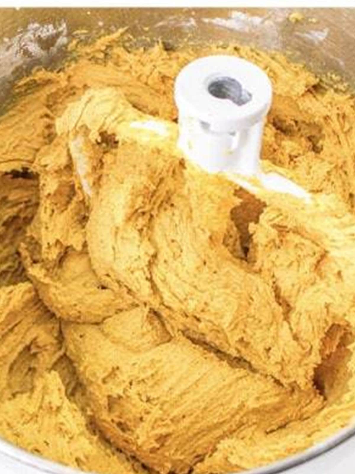 Soft pumpkin cookie dough fully mixed in a stand mixer bowl.