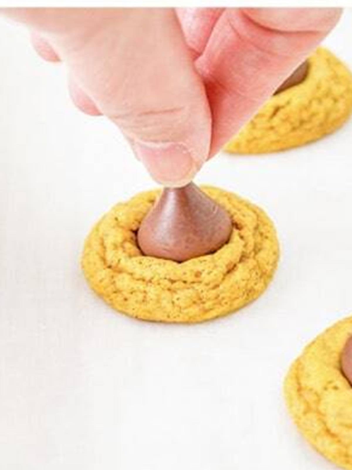 Pressing a Hershey Kiss into the center of a warm baked pumpkin cookie.