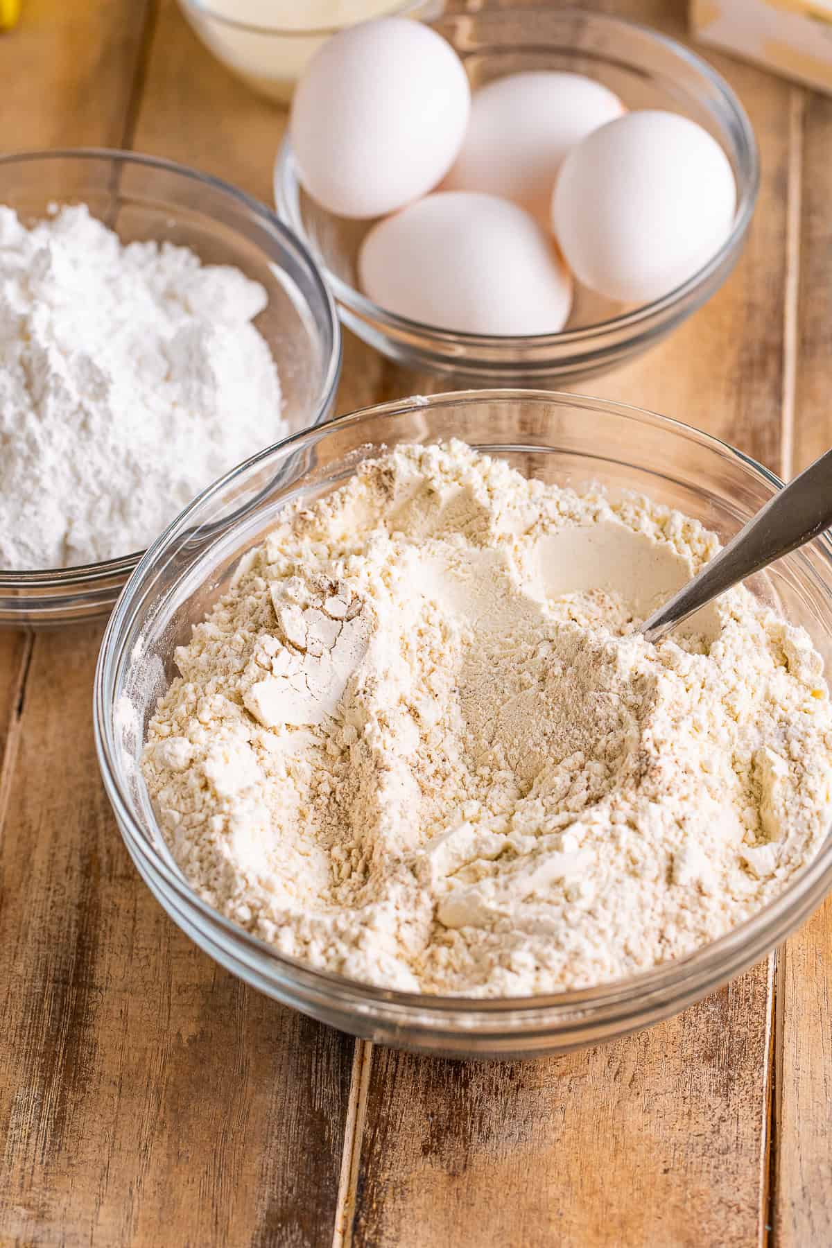 Flour, baking soda, pumpkin pie spice, and salt in a glass mixing bowl for pumpkin spice cake.