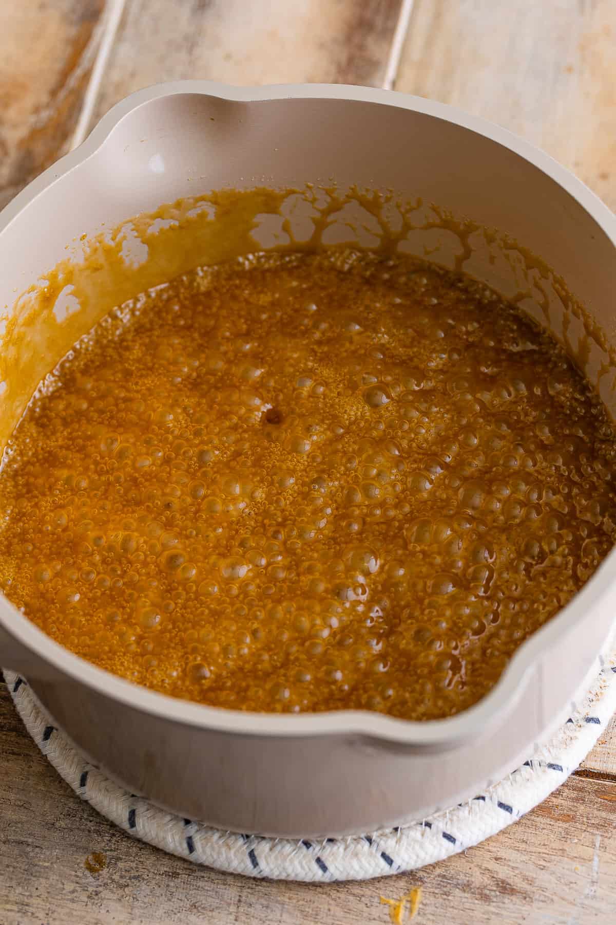 Brown sugar frosting bubbling in a saucepan as it comes to a boil.