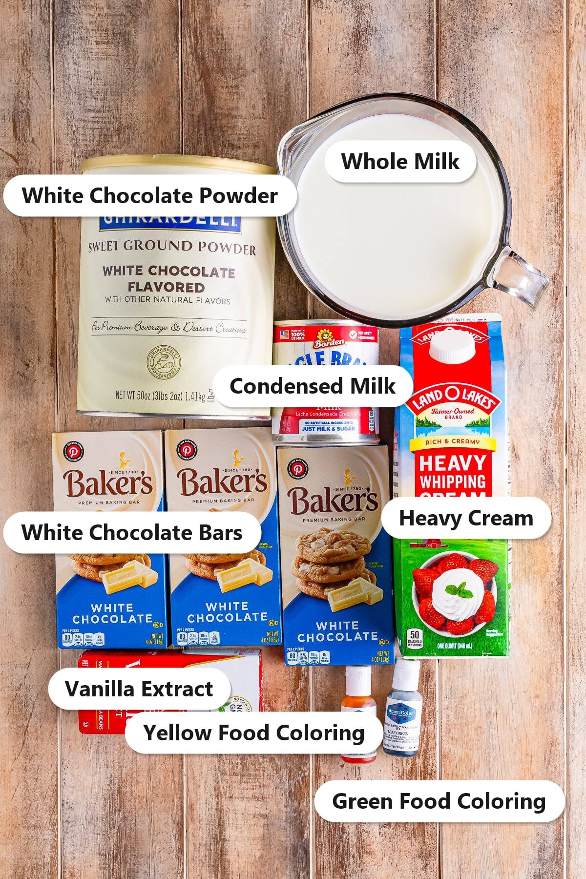 Labeled ingredients for Witches Brew hot chocolate including white chocolate powder, whole milk, sweetened condensed milk, heavy cream, white chocolate bars, vanilla extract, and green and yellow food coloring.