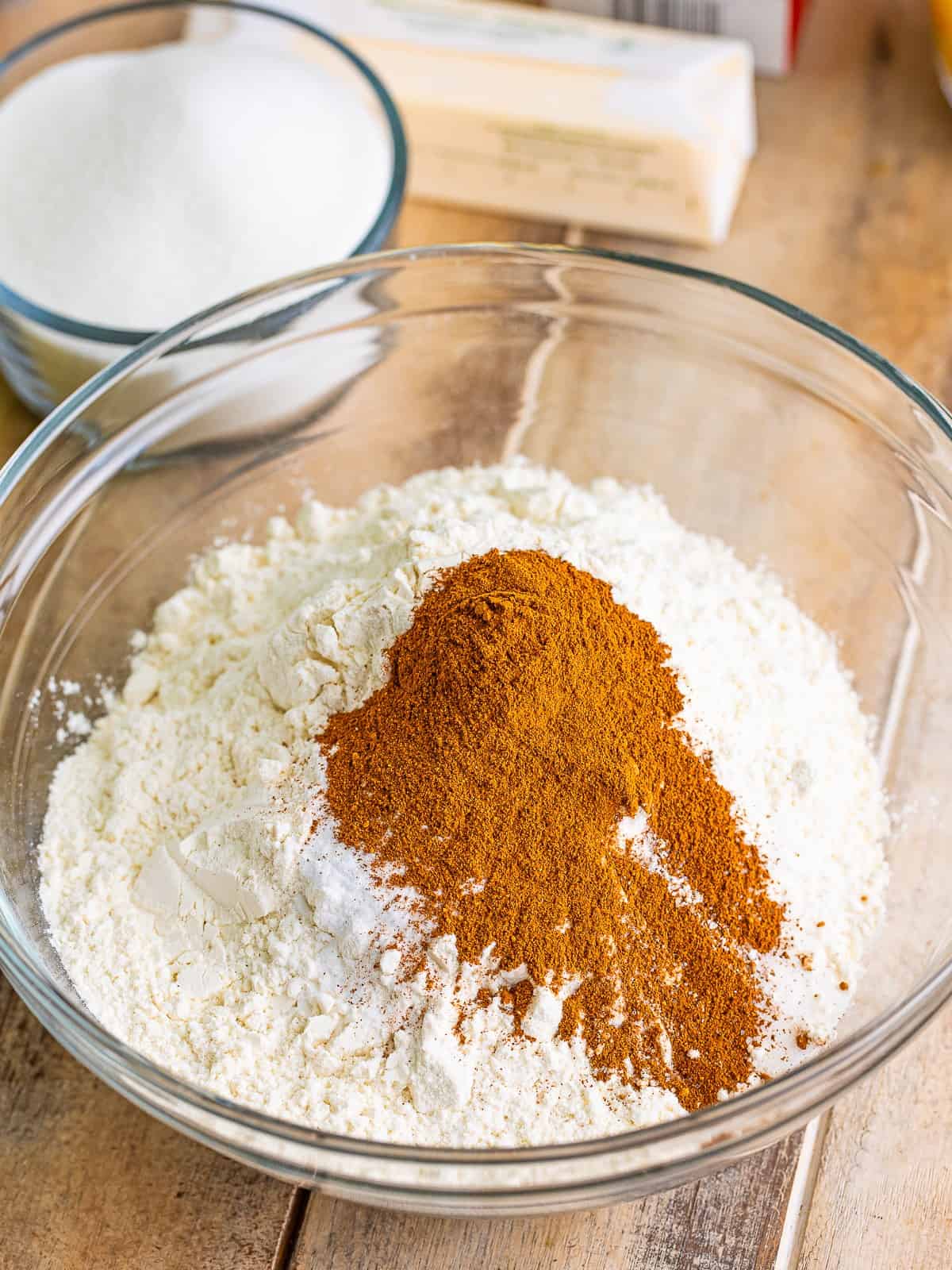 Flour with apple pie spice, baking soda and salt in a glass mixing bowl.