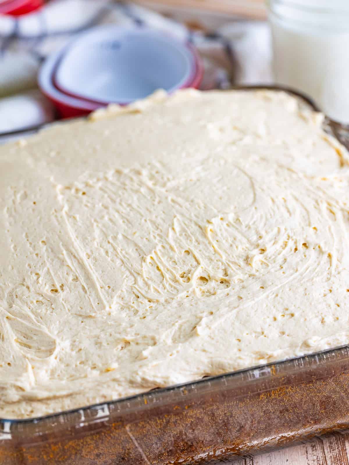 Brown sugar frosting spread over the top of the cooled apple spice cake in the baking dish.