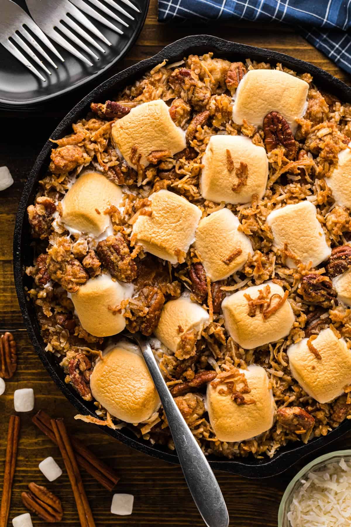 Sweet potatoes royale in a cast iron skillet topped with toasted marshmallows, pecans, and coconut.