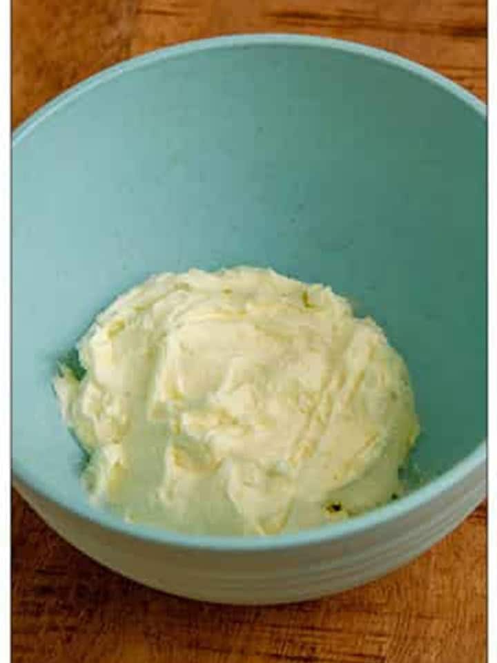 Cream cheese and butter blended until completely smooth in a blue bowl.
