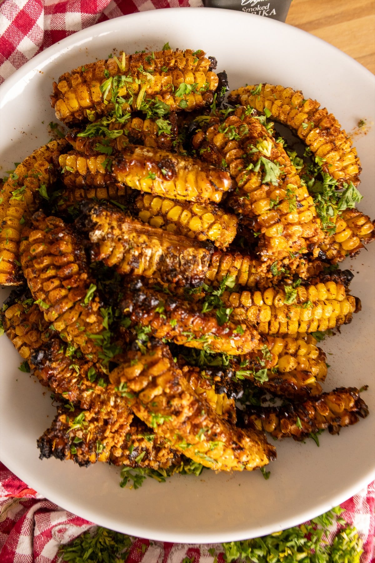 Overhead view of a platter of grilled corn ribs curled up with charred edges and fresh parsley.