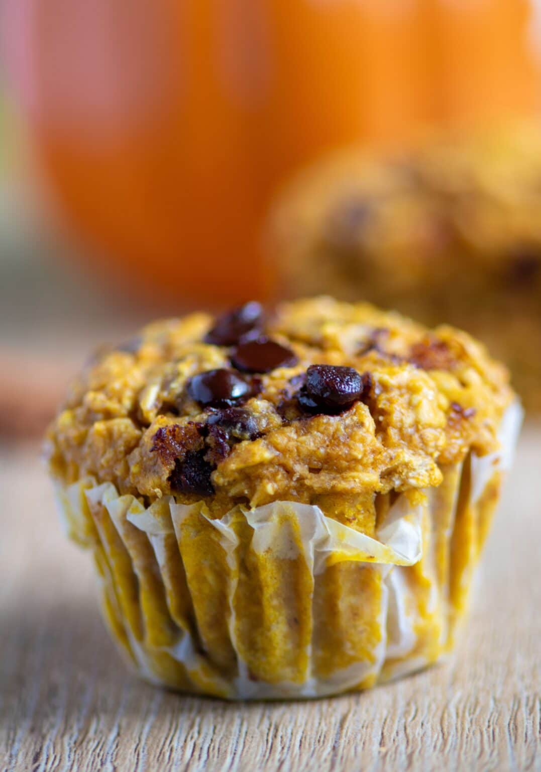 Healthy pumpkin oat muffins with chocolate chips cooling on a rack.