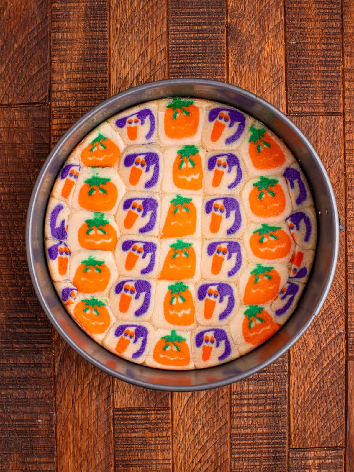 Baked sugar cookie crust in a springform pan with the pumpkin and ghost designs melted together.