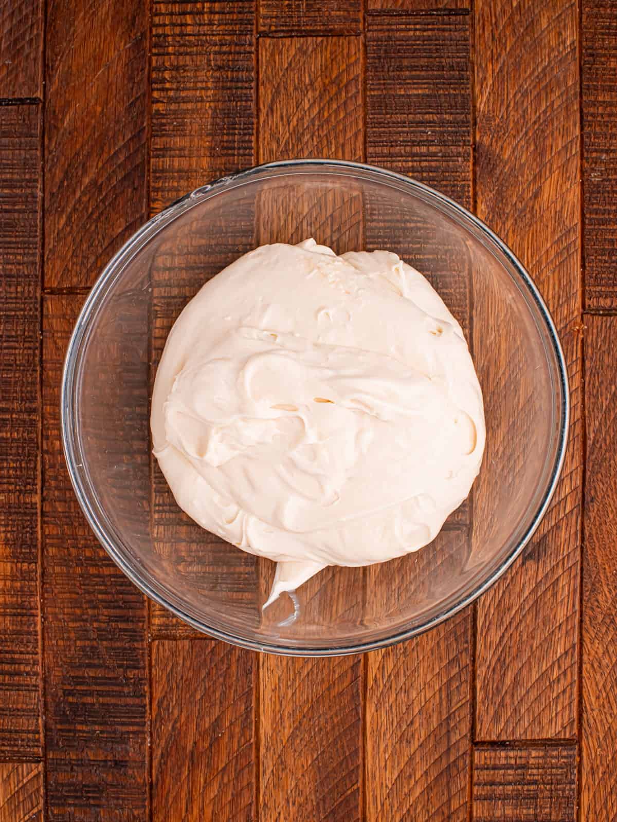 Cream cheese, confectioners sugar, and vanilla beaten smooth in a glass mixing bowl.