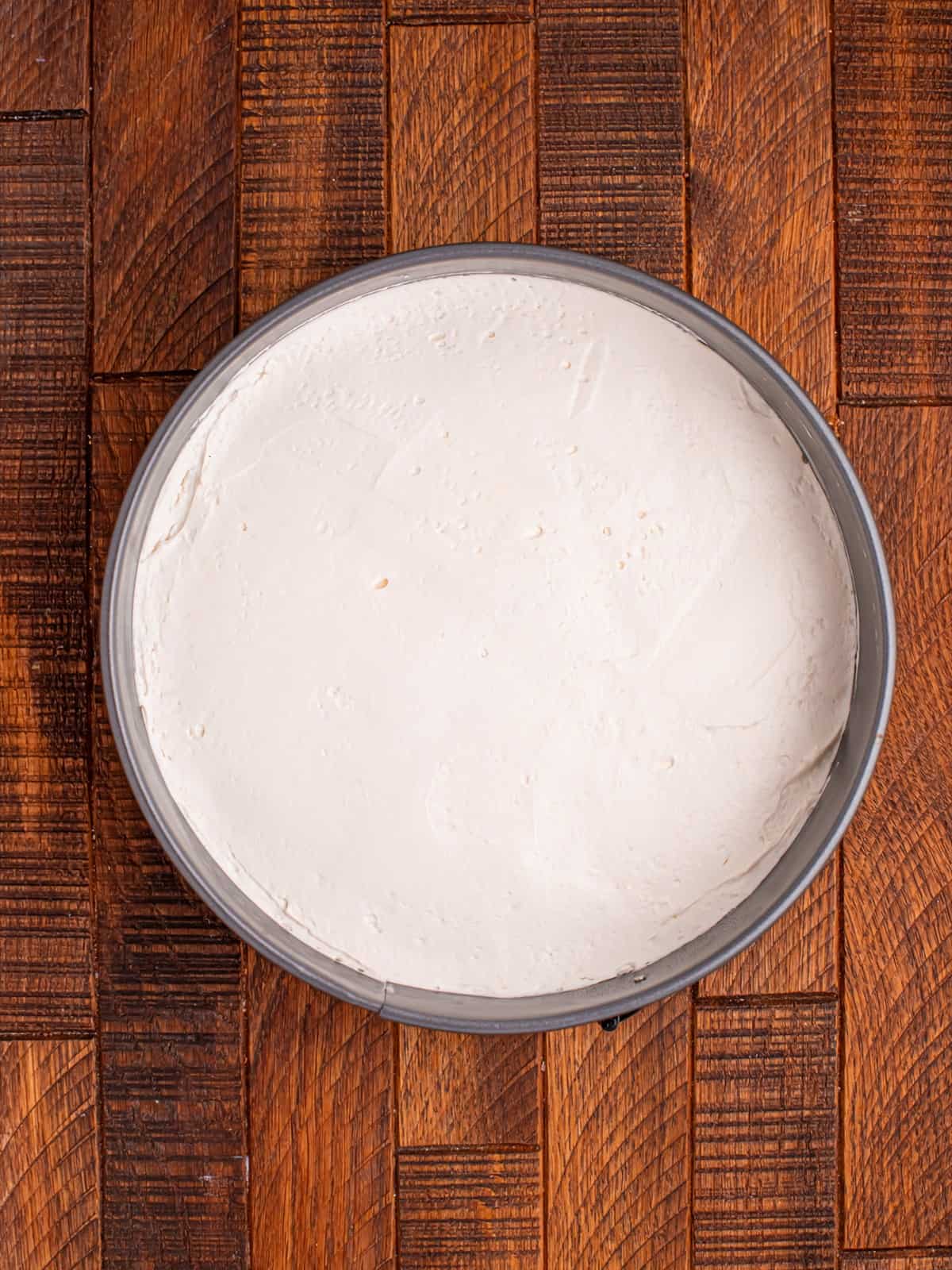 No bake cheesecake filling spread evenly over the cooled cookie crust in the springform pan.