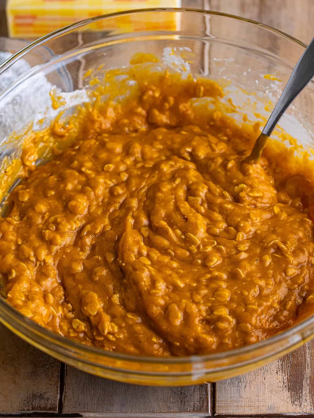 Thick pumpkin oatmeal muffin batter mixed and resting in a glass bowl.