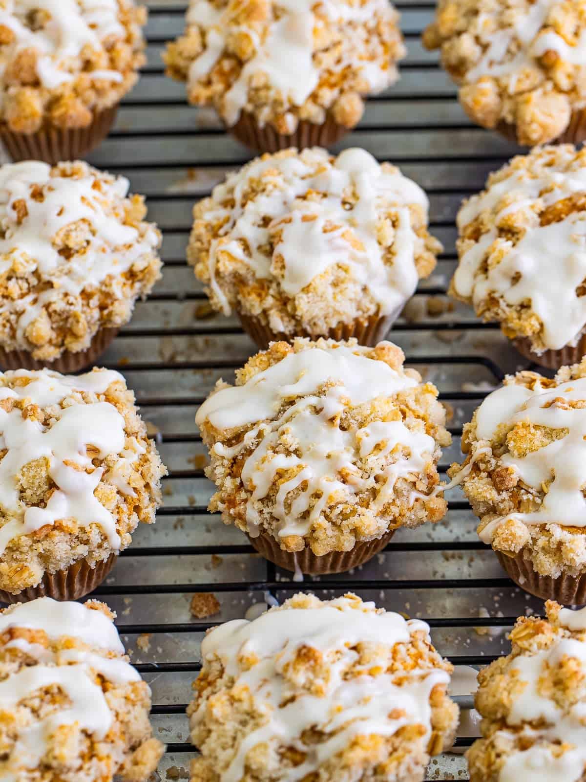 Baked pumpkin oatmeal muffins on a cooling rack with maple glaze drizzled over the streusel.