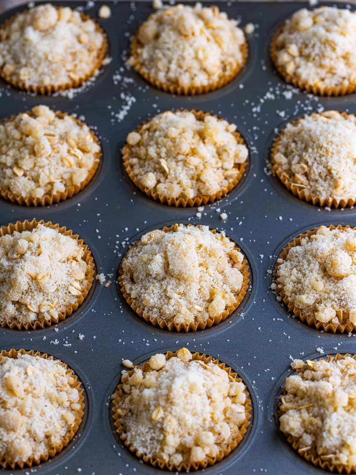 Muffin pan filled with pumpkin oatmeal batter and topped with streusel before baking.