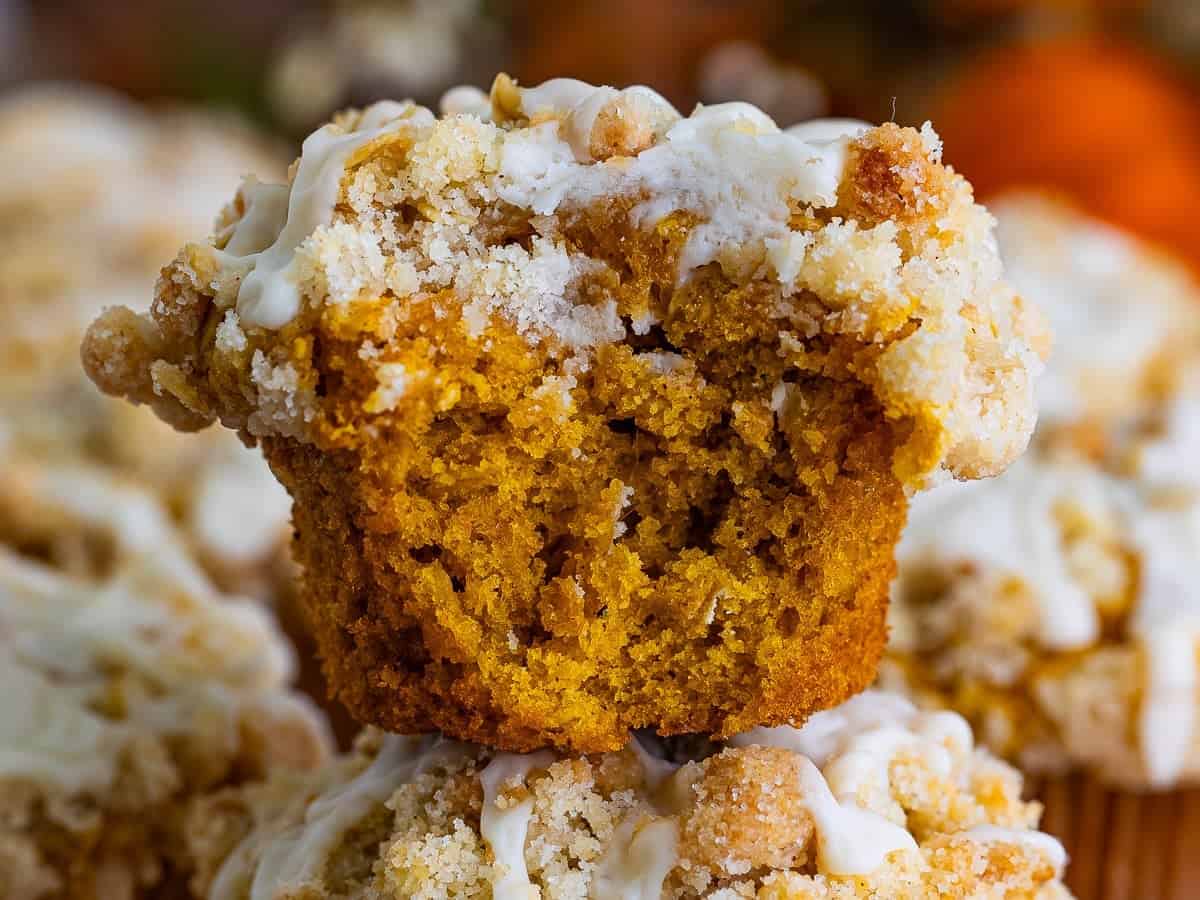 Pumpkin oatmeal muffin broken open to show the moist orange crumb studded with oats.