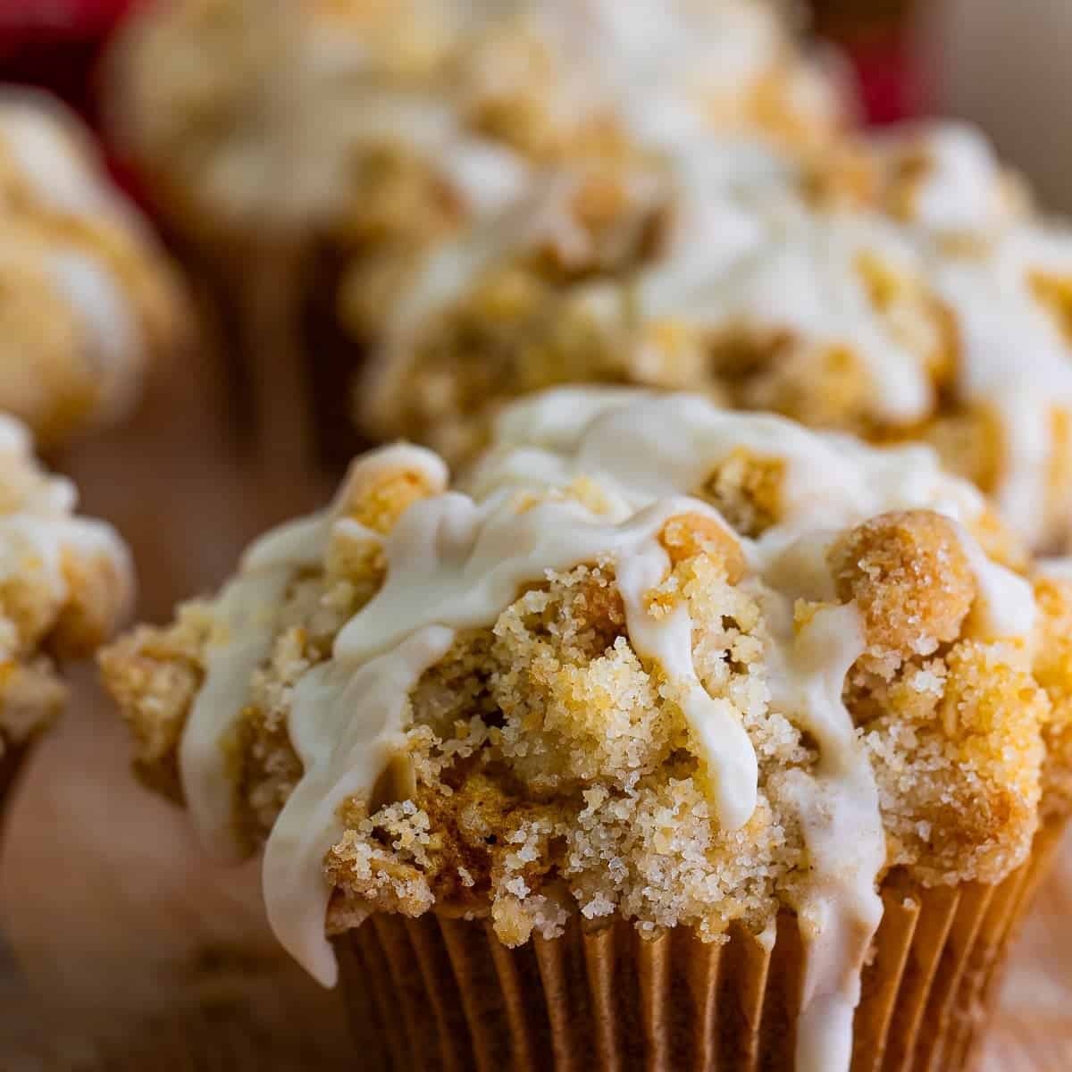 Pumpkin oatmeal muffin with streusel topping and maple glaze on a wooden board.