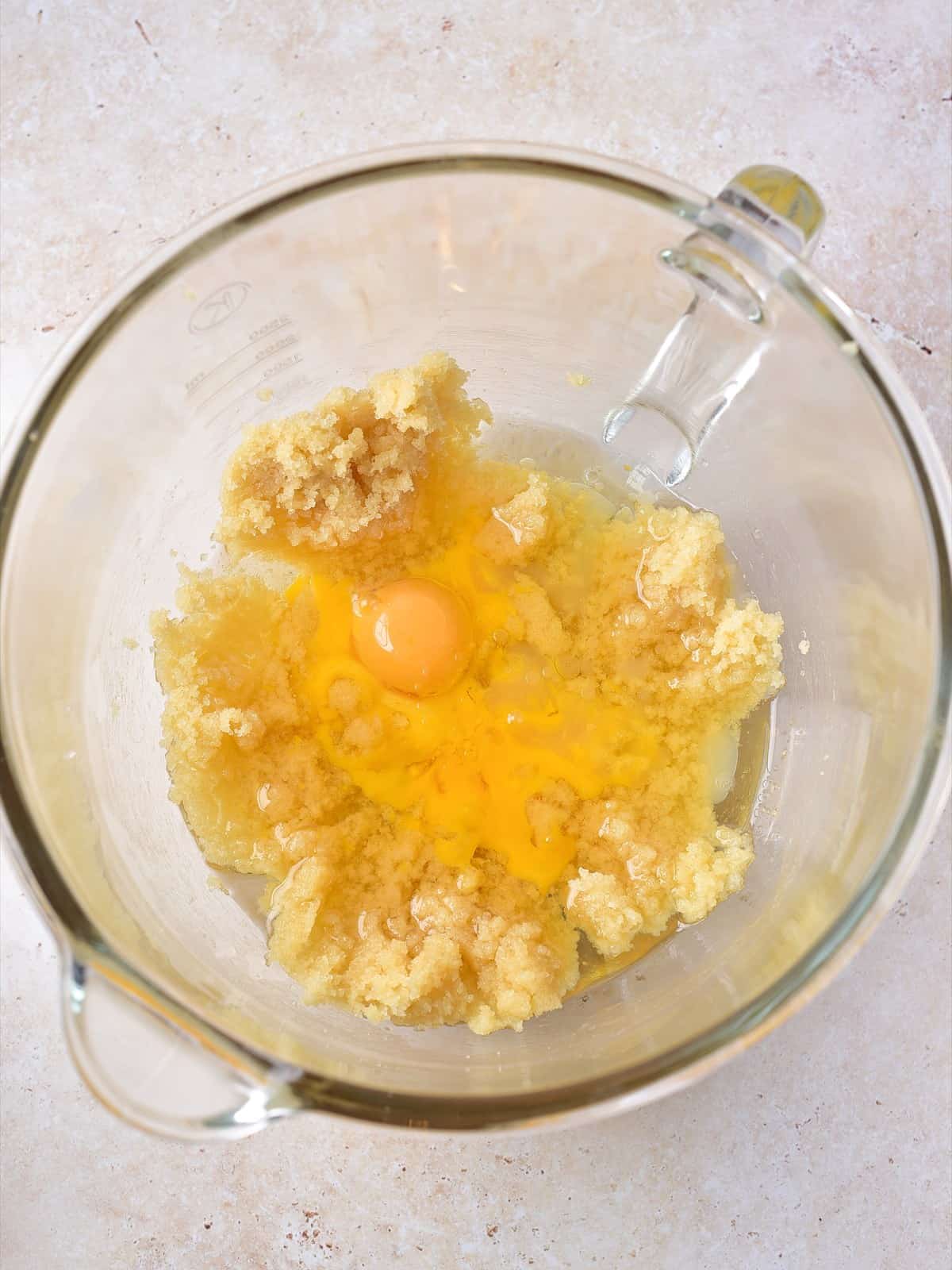 Egg yolks, oil, lemon juice, and vanilla added to creamed butter and brown sugar in a glass bowl.