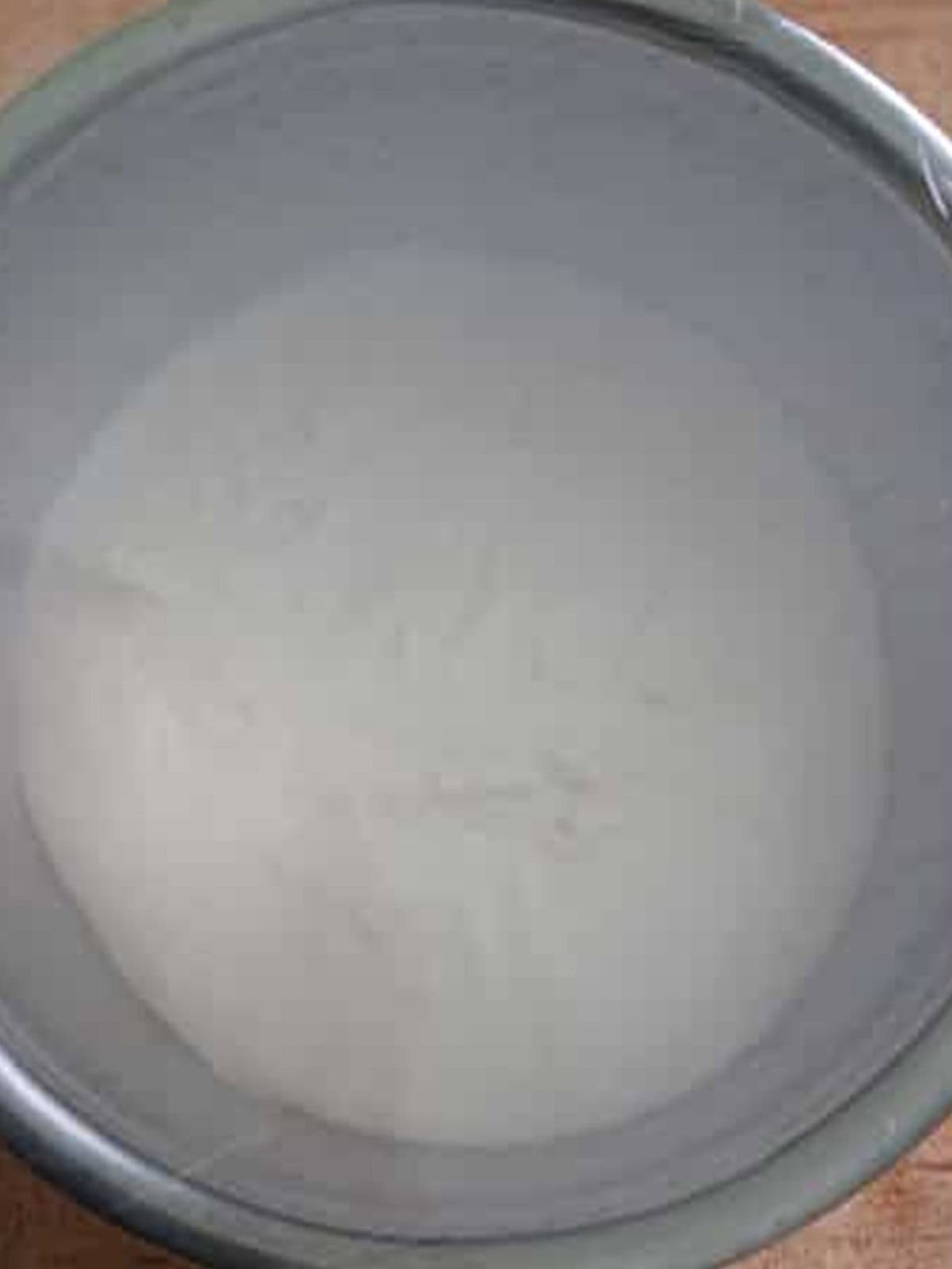 Salt bread dough doubled in size in a covered metal bowl after the first rise.