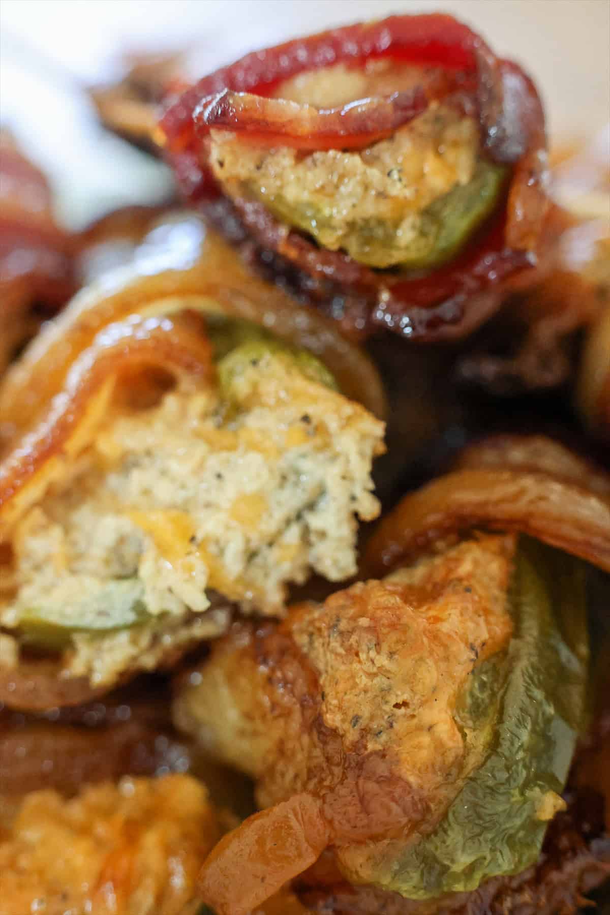 Close up of a smoked bacon wrapped jalapeno popper showing the melted cheesy filling.