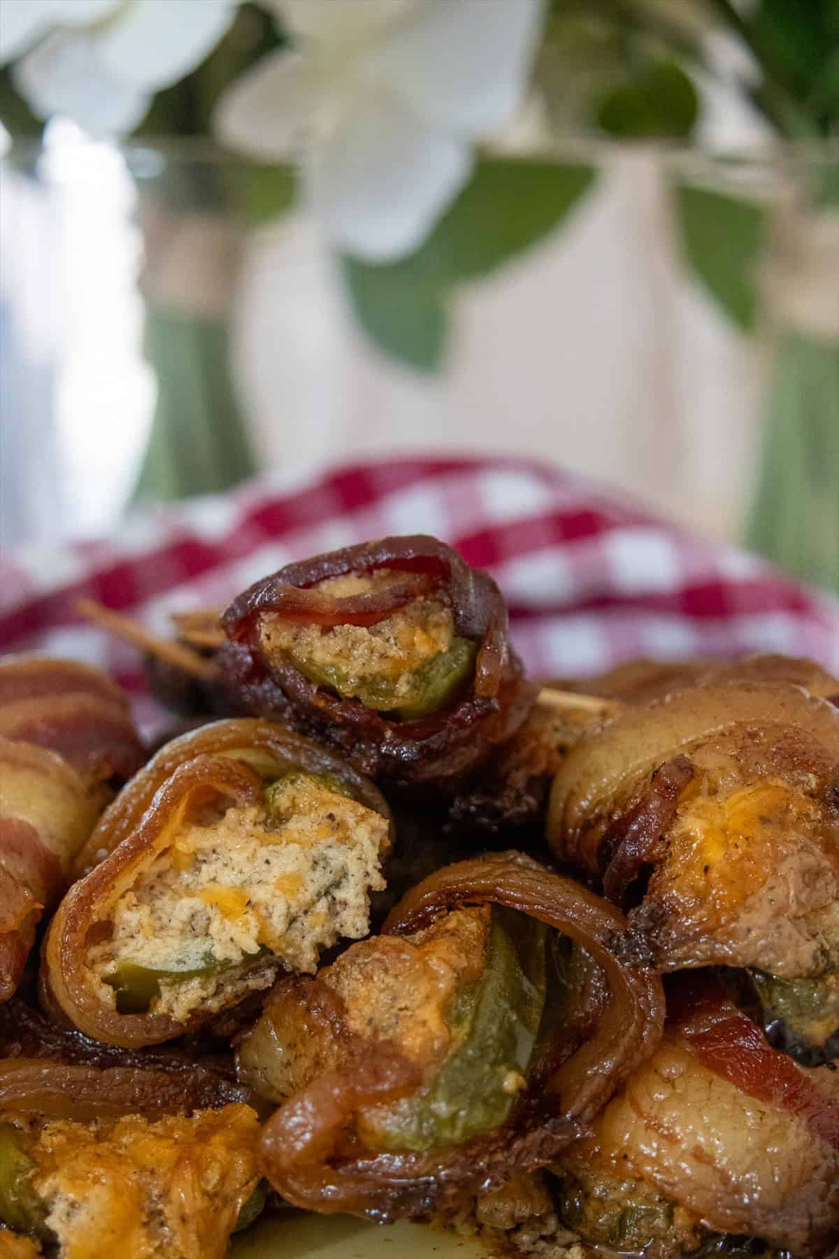 A platter of smoked bacon wrapped jalapeno poppers with crispy bacon and cheddar cream cheese filling.