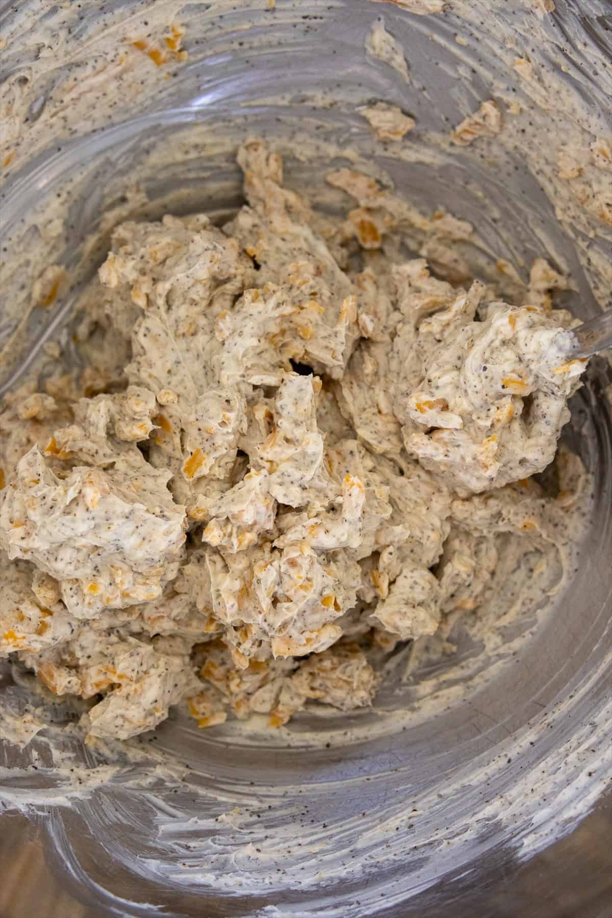 Cheddar cream cheese filling stirred together in a bowl for jalapeno poppers.