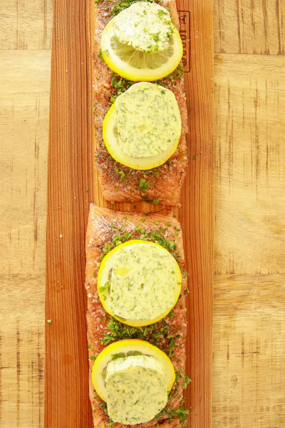 Pieces of butter topped with lemon slices lined down the center of the seasoned salmon fillets.