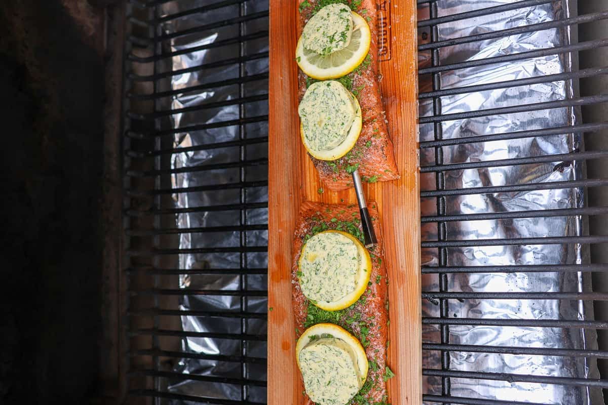 Cedar plank with the prepared salmon sitting on the grate inside the smoker.