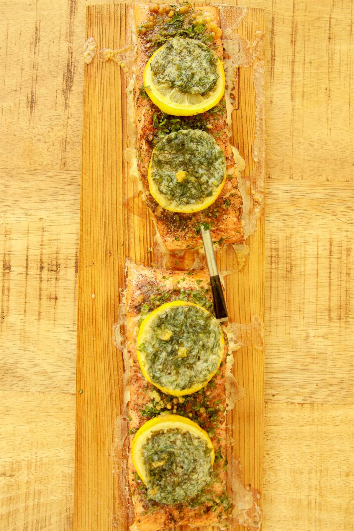 Finished cedar plank smoked salmon with golden edges, melted lemon butter, and toasted herbs.