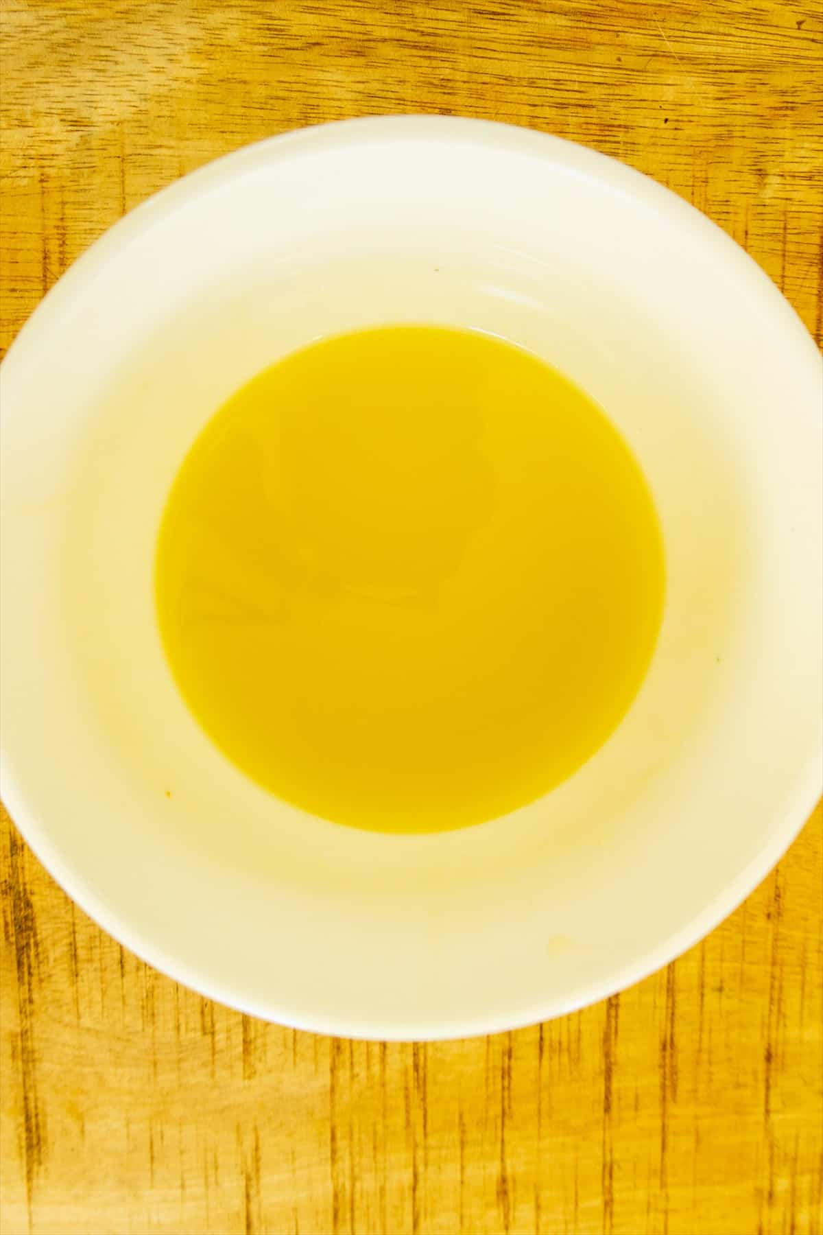 Honey lime dressing for watermelon feta salad whisked together in a small white bowl.