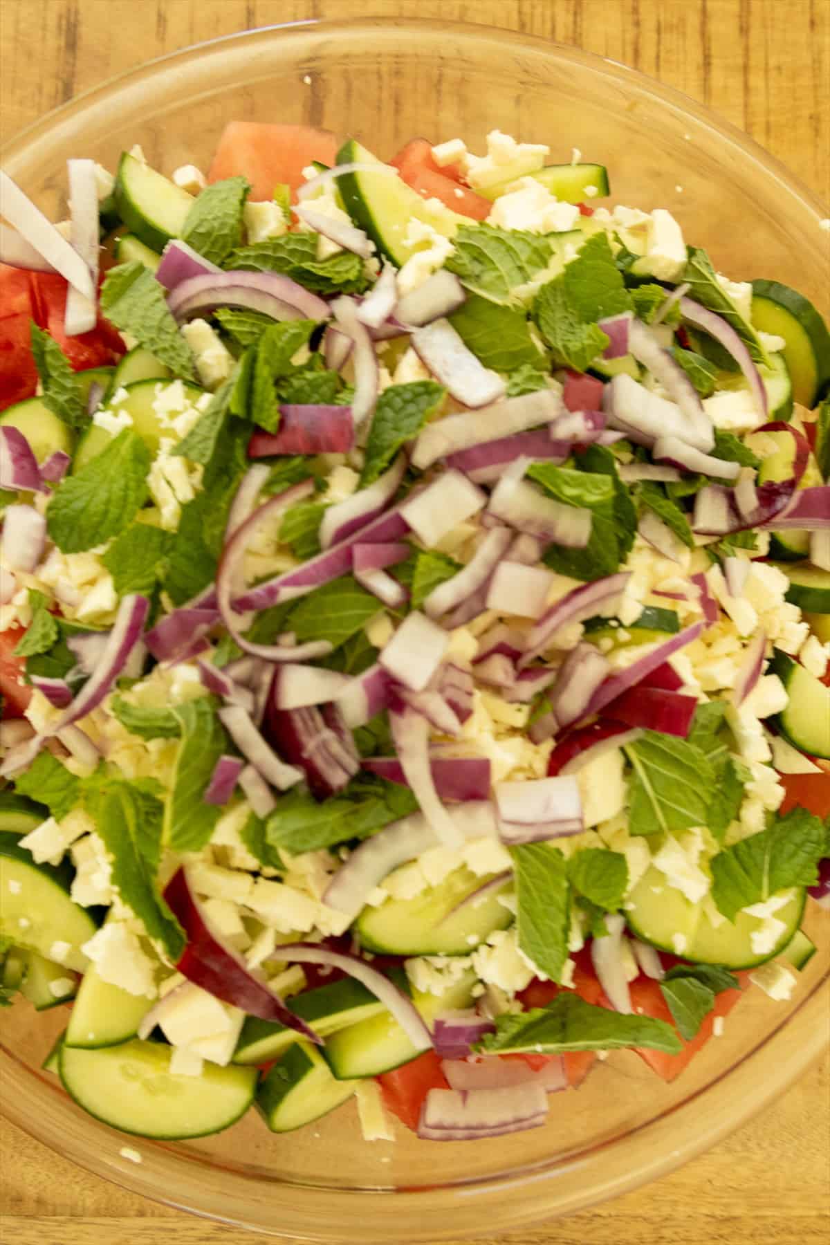 Watermelon feta salad tossed gently with sliced red onion, torn mint, and crumbled feta before serving.