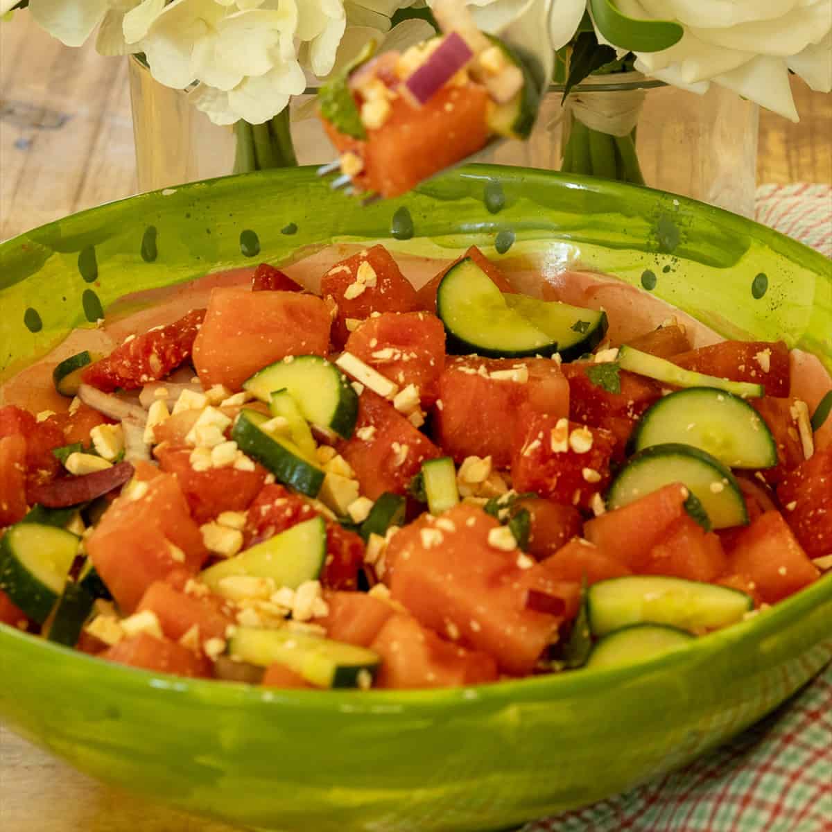 Watermelon feta salad in a green watermelon bowl with a fork lifting a bite of melon, feta, and red onion.