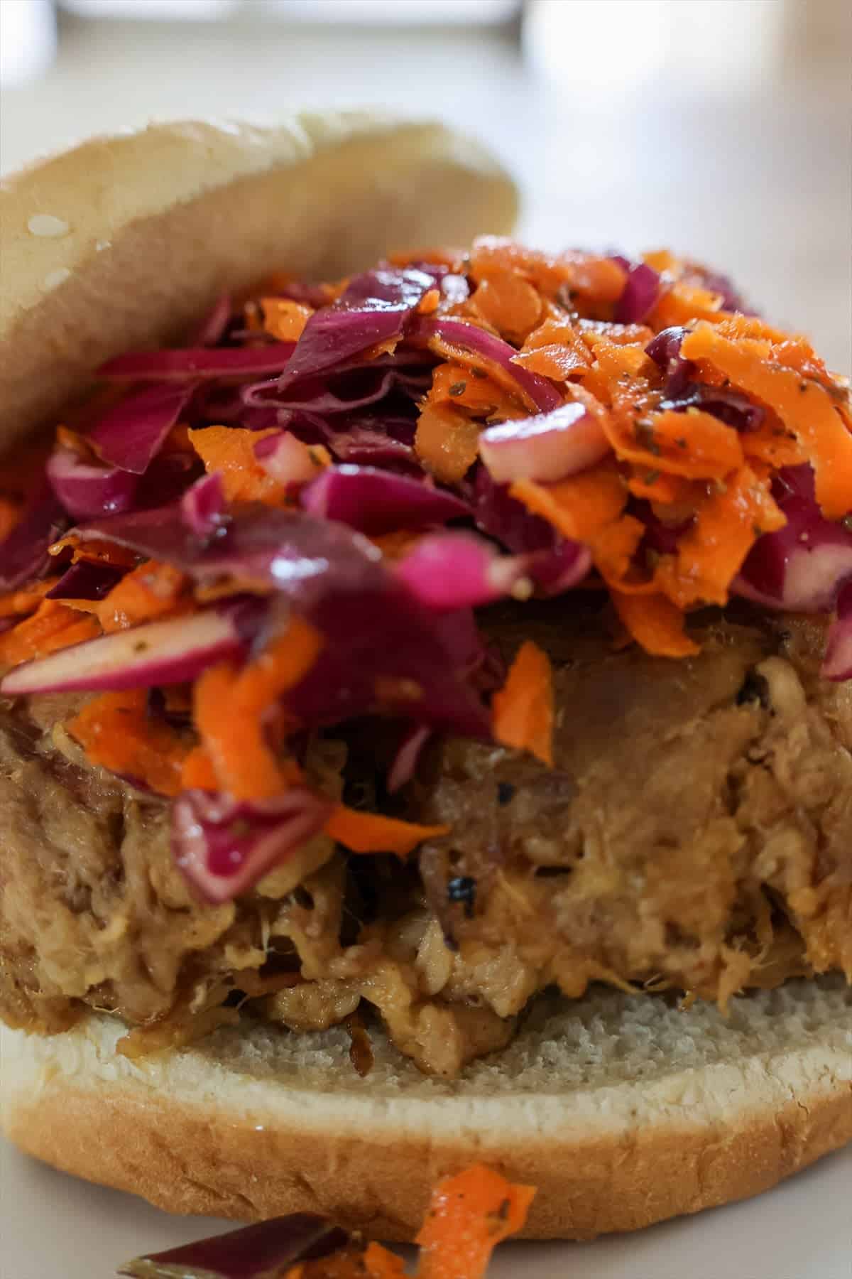 Carolina vinegar slaw piled on top of a pulled pork sandwich on a toasted bun.