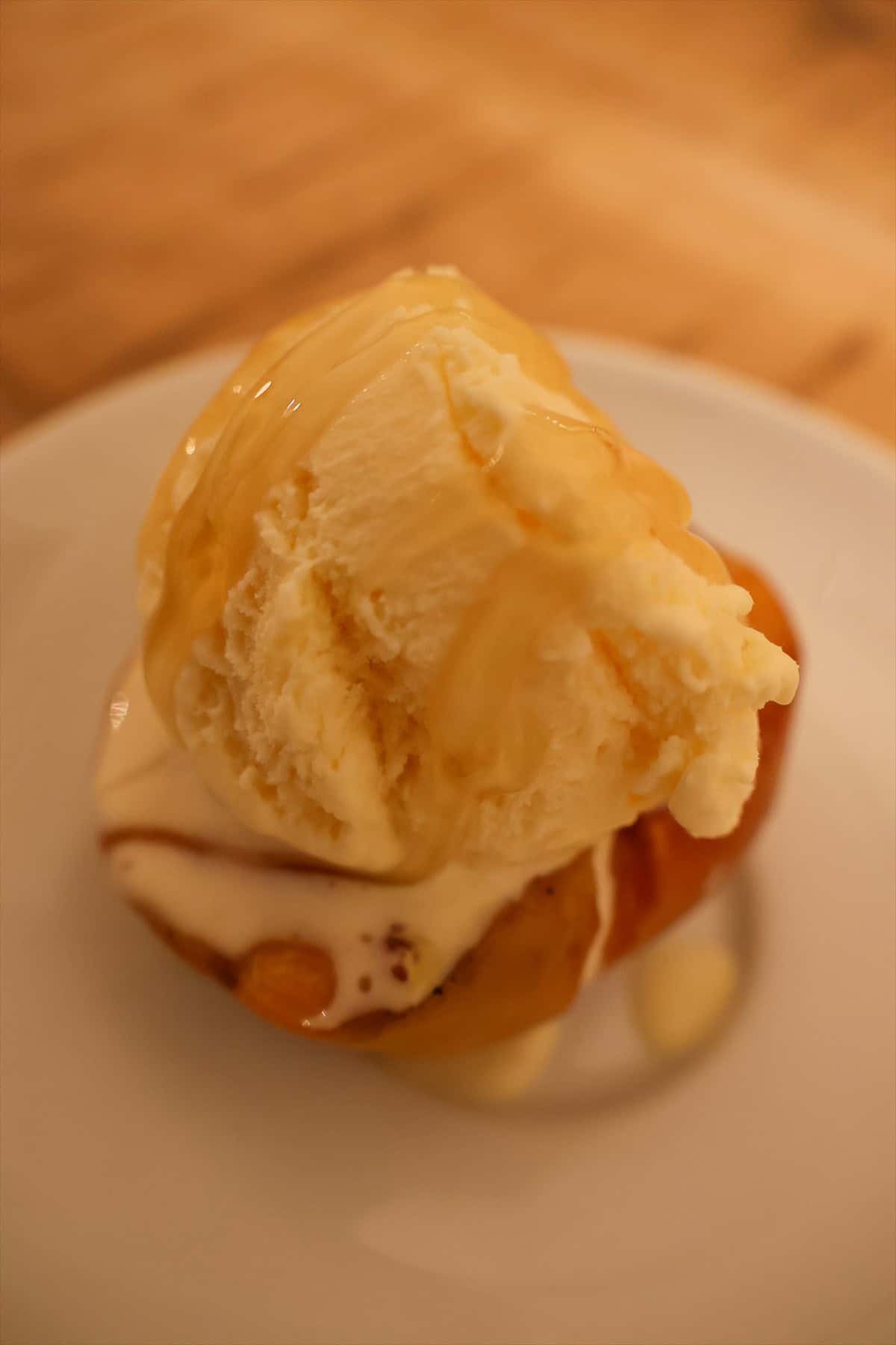 Grilled peach half topped with a scoop of vanilla ice cream starting to melt on a plate.