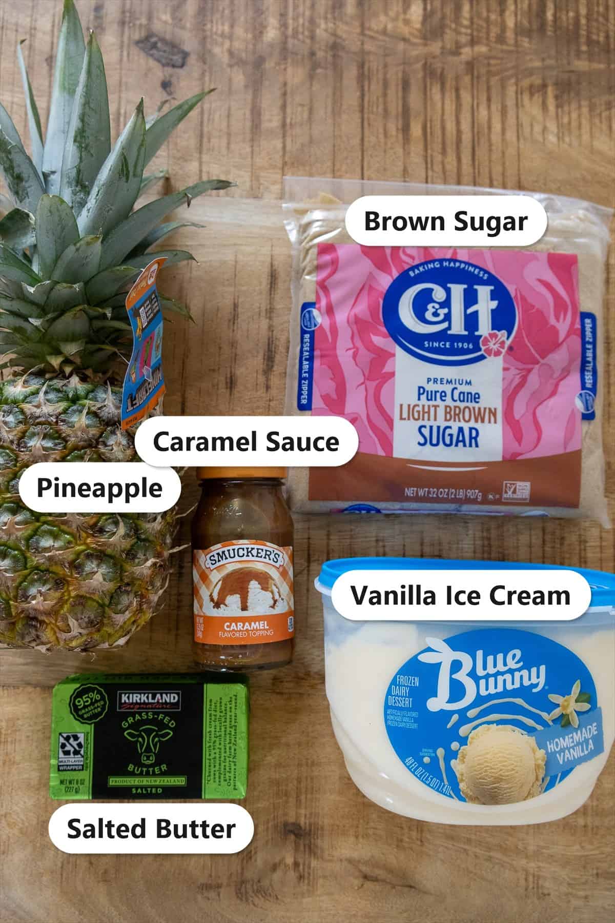 Labeled ingredients for grilled pineapple sundaes including fresh pineapple, brown sugar, caramel sauce, vanilla ice cream, and salted butter.