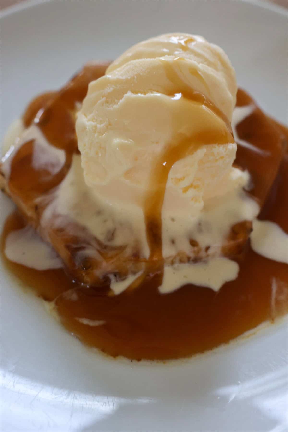 Grilled pineapple sundae topped with vanilla ice cream and a caramel sauce drizzle.