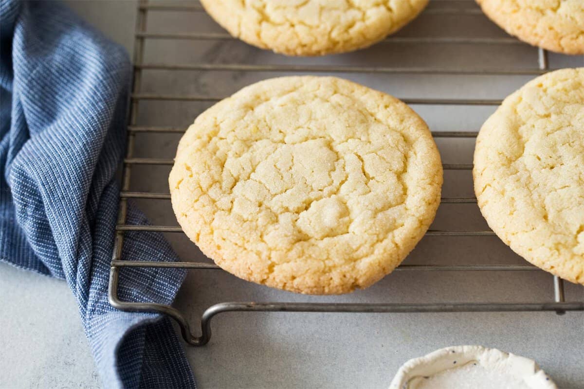 Golden small batch sugar cookies with crackled tops cooling on a wire rack.