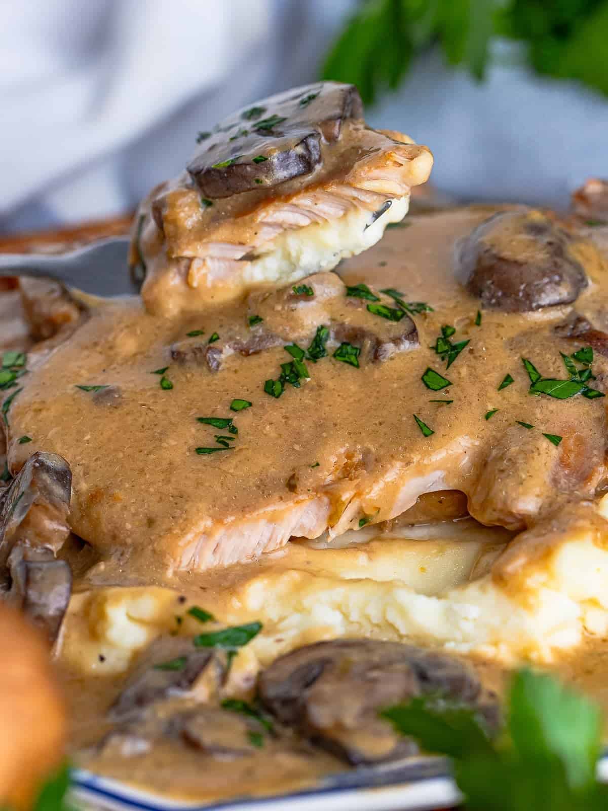 Close up of a forkful of slow cooker pork chop with mushroom gravy and mashed potatoes.