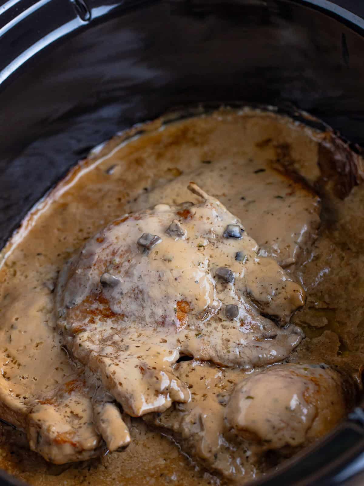 Tender cooked pork chops in creamy mushroom gravy inside the slow cooker.
