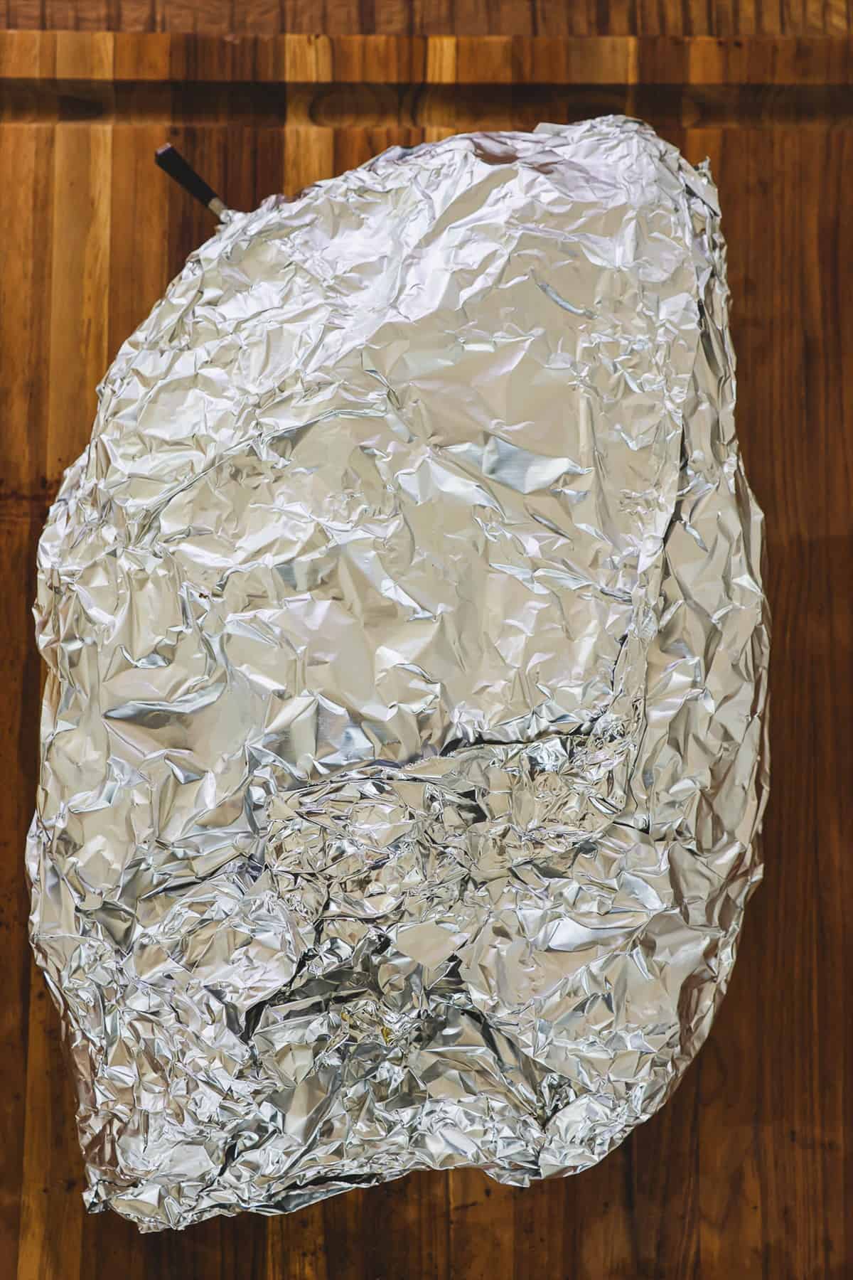 Brisket wrapped in two layers of heavy duty aluminum foil on a cutting board.
