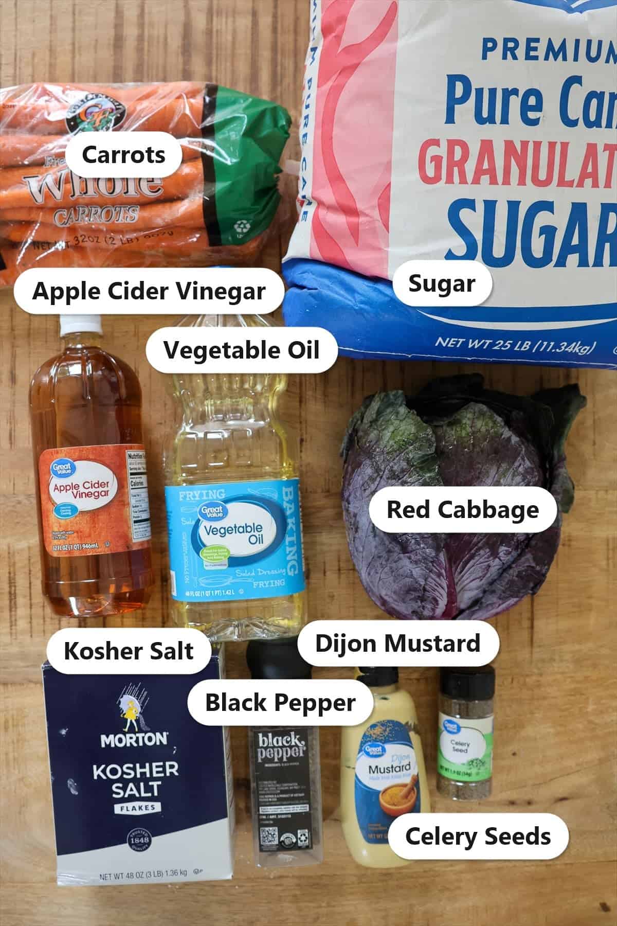 Labeled ingredients for vinegar coleslaw including red cabbage, carrots, apple cider vinegar, sugar, vegetable oil, Dijon mustard, celery seeds, kosher salt, and black pepper.