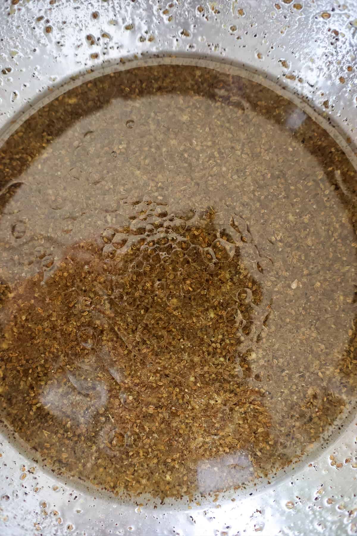 Apple cider vinegar dressing with celery seeds and black pepper whisked together in a glass bowl.